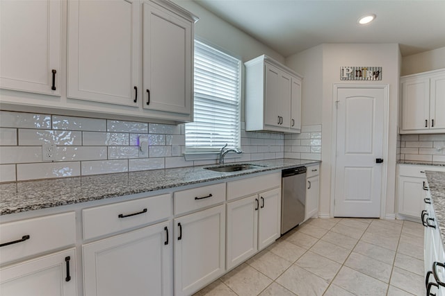 kitchen with dishwasher, sink, light tile patterned floors, and white cabinets