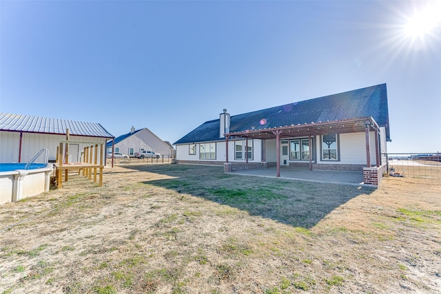 rear view of property featuring a fenced in pool and a patio area