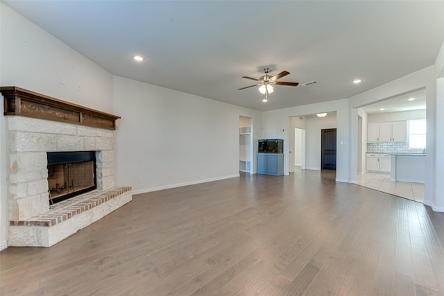 unfurnished living room featuring ceiling fan, a fireplace, and light hardwood / wood-style floors