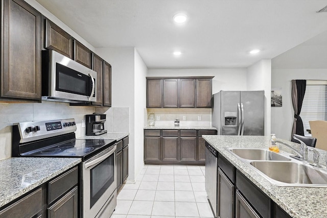 kitchen with dark brown cabinetry, sink, light tile patterned floors, and appliances with stainless steel finishes