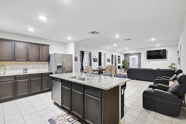 kitchen with sink, light tile patterned floors, a center island with sink, and appliances with stainless steel finishes