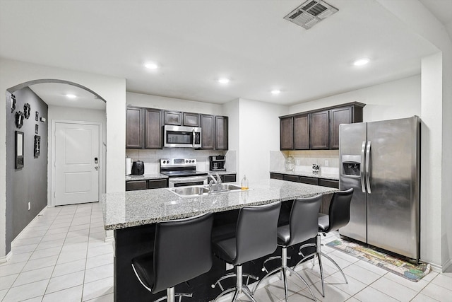 kitchen with tasteful backsplash, sink, dark brown cabinets, and appliances with stainless steel finishes