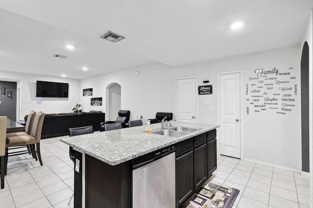 kitchen with sink, dishwasher, an island with sink, and light tile patterned floors