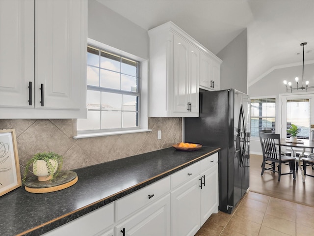 kitchen featuring pendant lighting, dark countertops, lofted ceiling, white cabinets, and a chandelier