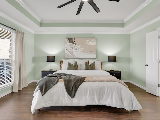 bedroom featuring dark wood-style floors, a tray ceiling, baseboards, and crown molding