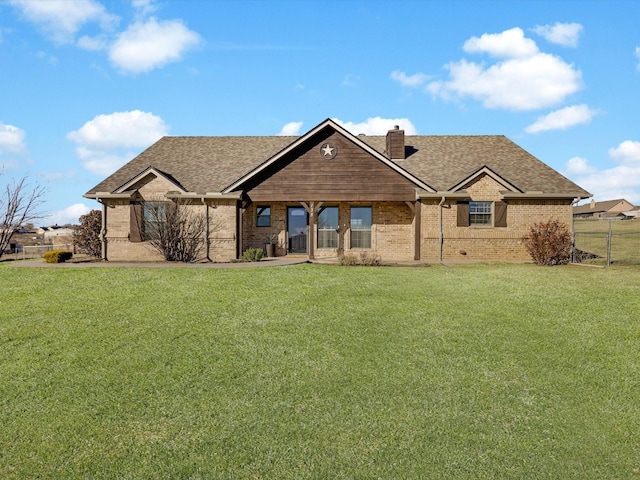 view of front of home with a front yard, brick siding, a chimney, and roof with shingles