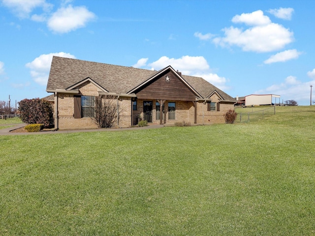 view of front of property with brick siding, a front yard, fence, and a shingled roof