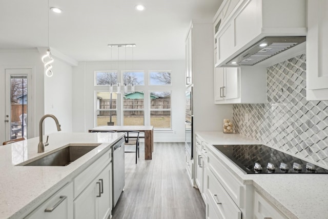 kitchen featuring appliances with stainless steel finishes, pendant lighting, sink, white cabinets, and custom range hood