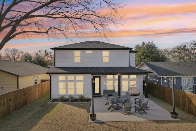 rear view of property featuring a yard, a shingled roof, a fenced backyard, and a patio area