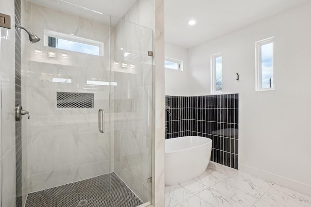 full bath with recessed lighting, a freestanding bath, a shower stall, tile walls, and marble finish floor