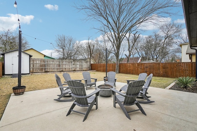 view of patio with an outbuilding, a fire pit, a fenced backyard, and a shed