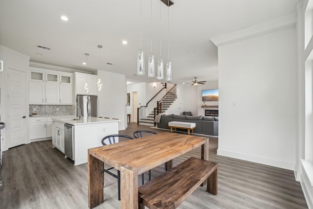 dining space with dark wood-type flooring, ceiling fan, ornamental molding, and sink