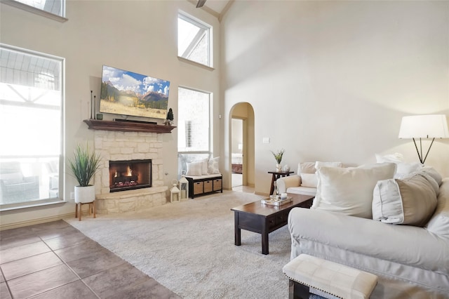 living room with a towering ceiling, light colored carpet, and a fireplace