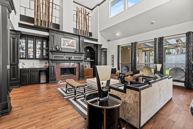 living room featuring bar area, a towering ceiling, beverage cooler, and hardwood / wood-style flooring