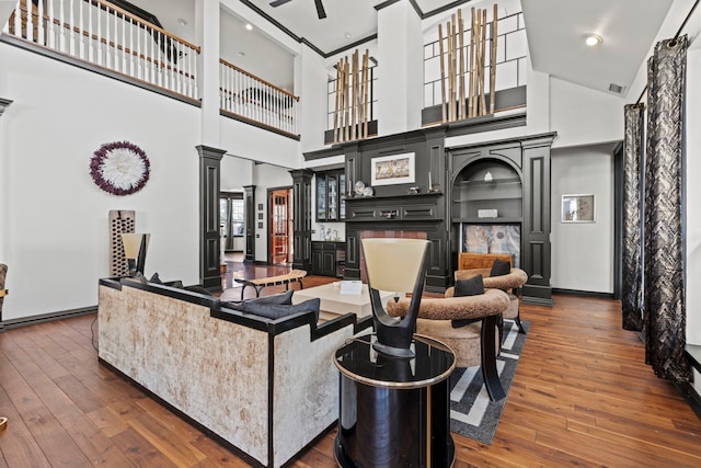 living room featuring ornate columns, dark hardwood / wood-style flooring, and a high ceiling