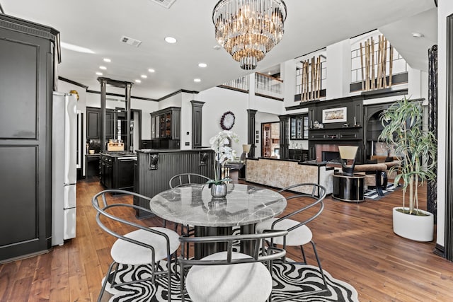 dining space with dark wood-type flooring, ornamental molding, and a chandelier