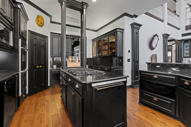 kitchen featuring appliances with stainless steel finishes, backsplash, a center island, light hardwood / wood-style floors, and ornate columns