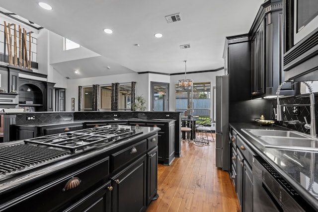 kitchen with stainless steel refrigerator, sink, dishwashing machine, light hardwood / wood-style floors, and an inviting chandelier