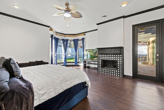 bedroom featuring a tile fireplace, ornamental molding, dark hardwood / wood-style floors, and ceiling fan