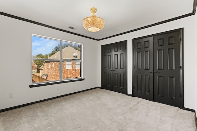 unfurnished bedroom with multiple closets, light colored carpet, and crown molding