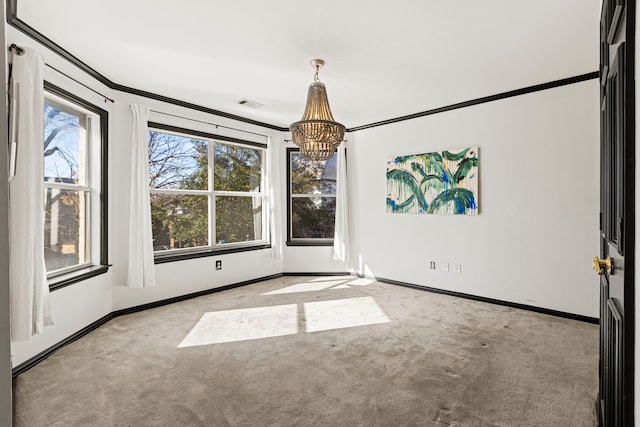 carpeted spare room featuring ornamental molding and a chandelier