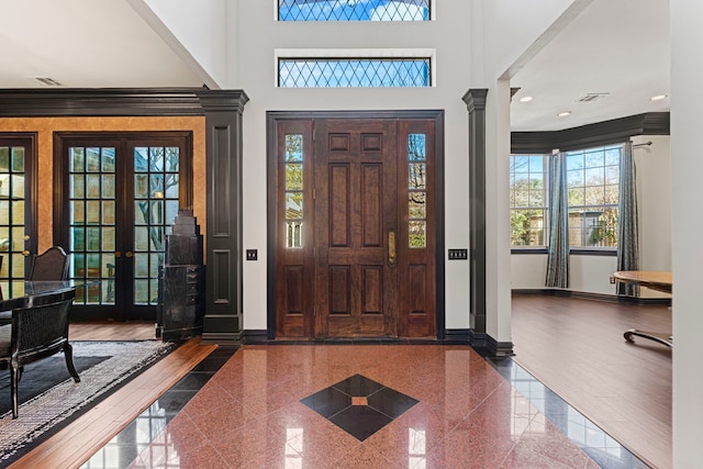 foyer with ornamental molding, a high ceiling, and ornate columns