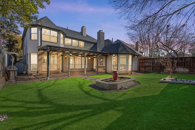 back house at dusk with a pergola, a yard, and a patio area