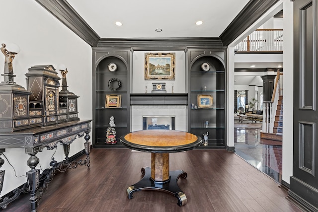 interior space featuring hardwood / wood-style flooring, ornamental molding, a fireplace, and built in features