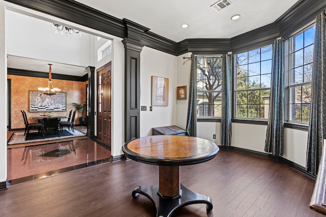 interior space with crown molding, a notable chandelier, decorative columns, and a wealth of natural light