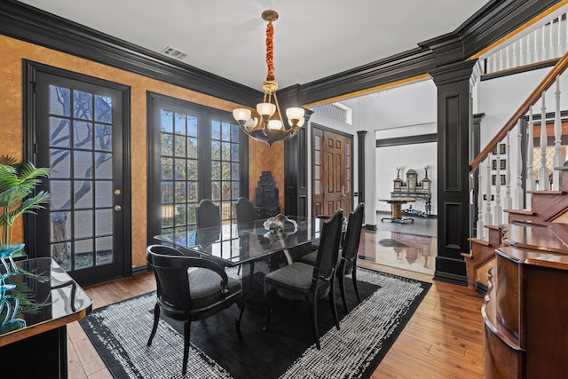 dining area featuring crown molding, decorative columns, an inviting chandelier, and light hardwood / wood-style flooring