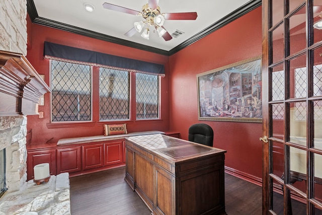 office space featuring crown molding, ceiling fan, dark hardwood / wood-style floors, and a stone fireplace