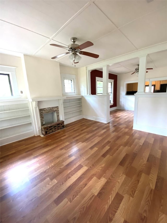 unfurnished living room with a stone fireplace, hardwood / wood-style floors, and ceiling fan