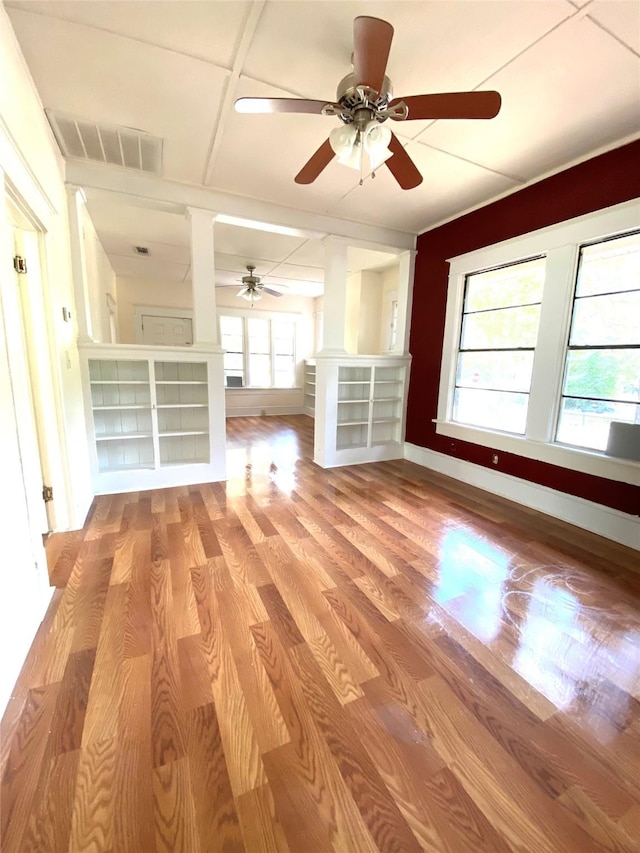 unfurnished living room with decorative columns, ceiling fan, and light wood-type flooring