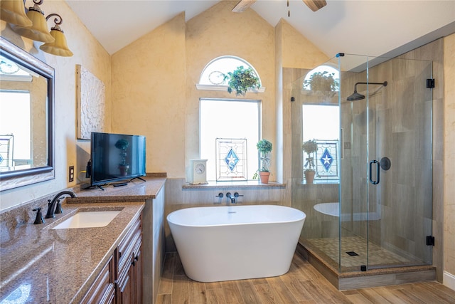 bathroom with vaulted ceiling, shower with separate bathtub, wood-type flooring, vanity, and ceiling fan