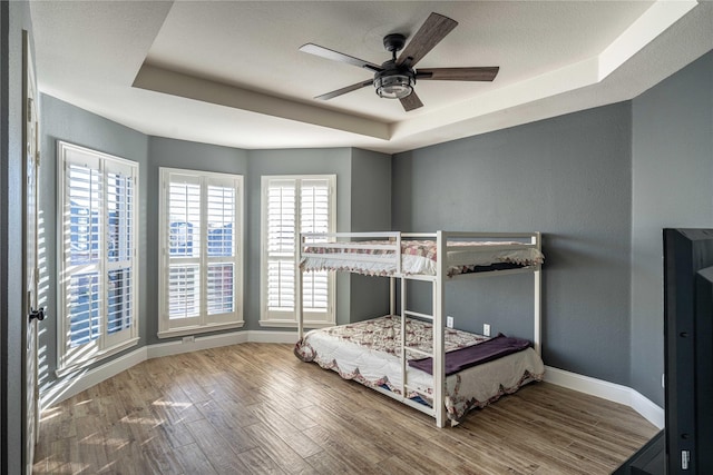 bedroom featuring hardwood / wood-style floors, ceiling fan, and a tray ceiling