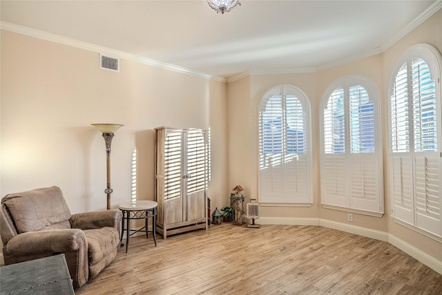 sitting room with ornamental molding and light wood-type flooring