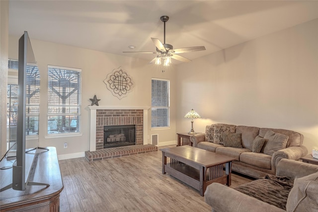 living room featuring a brick fireplace, light hardwood / wood-style flooring, and ceiling fan