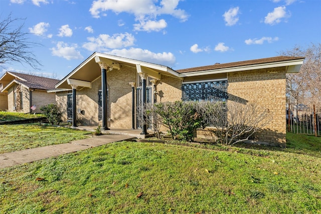 mid-century modern home with fence, a front lawn, and brick siding