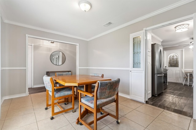 tiled dining room featuring ornamental molding, visible vents, ceiling fan, and baseboards