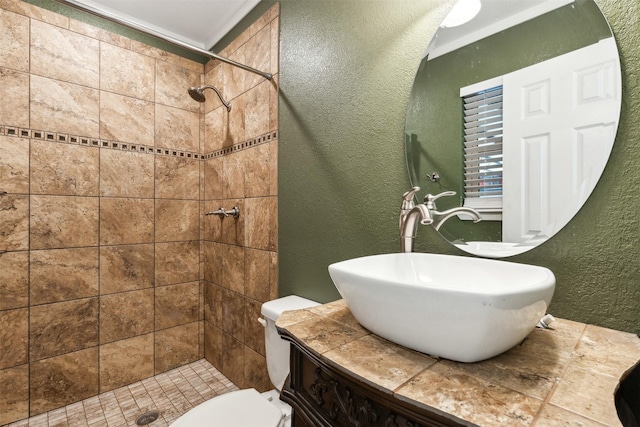 bathroom with a textured wall, a sink, a shower stall, and toilet