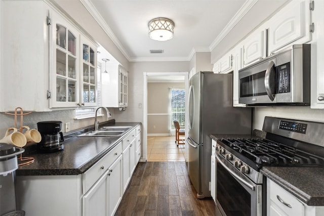 kitchen featuring stainless steel appliances, dark countertops, white cabinetry, and a sink