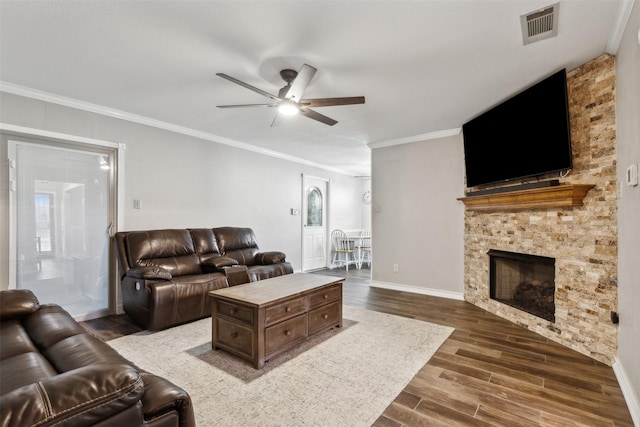 living room featuring dark hardwood / wood-style flooring, crown molding, a stone fireplace, and ceiling fan