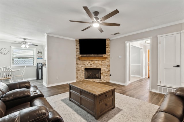 living room with a fireplace, wood-type flooring, ornamental molding, and ceiling fan