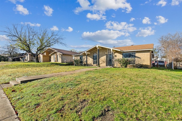 view of front of property with brick siding, fence, and a front yard