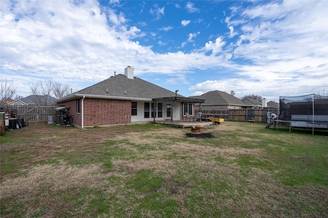 back of property with a trampoline, a yard, and a patio area