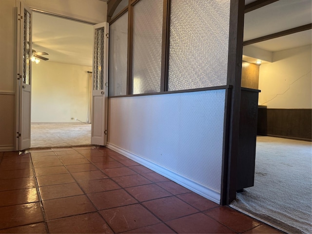 corridor featuring beam ceiling and carpet