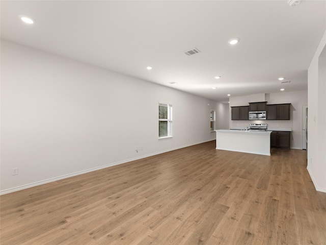 unfurnished living room featuring recessed lighting, baseboards, and light wood-type flooring