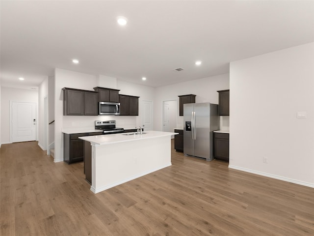 kitchen featuring a kitchen island with sink, light countertops, light wood finished floors, stainless steel appliances, and recessed lighting