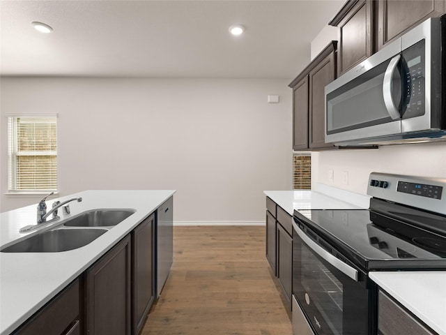 kitchen featuring light countertops, stainless steel appliances, a sink, and dark brown cabinets