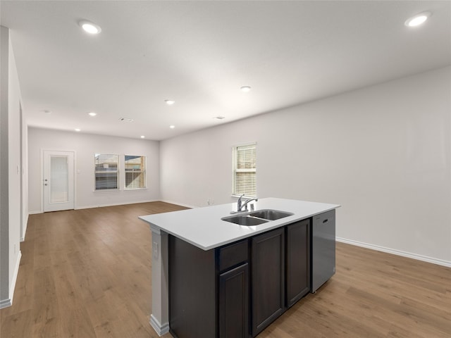 kitchen featuring a sink, light wood-style flooring, dishwasher, and a center island with sink